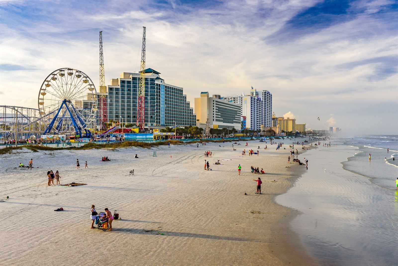 Daytona Beach sand at low tide, with a Ferris wheel, a roller coaster and oceanfront hotels behind